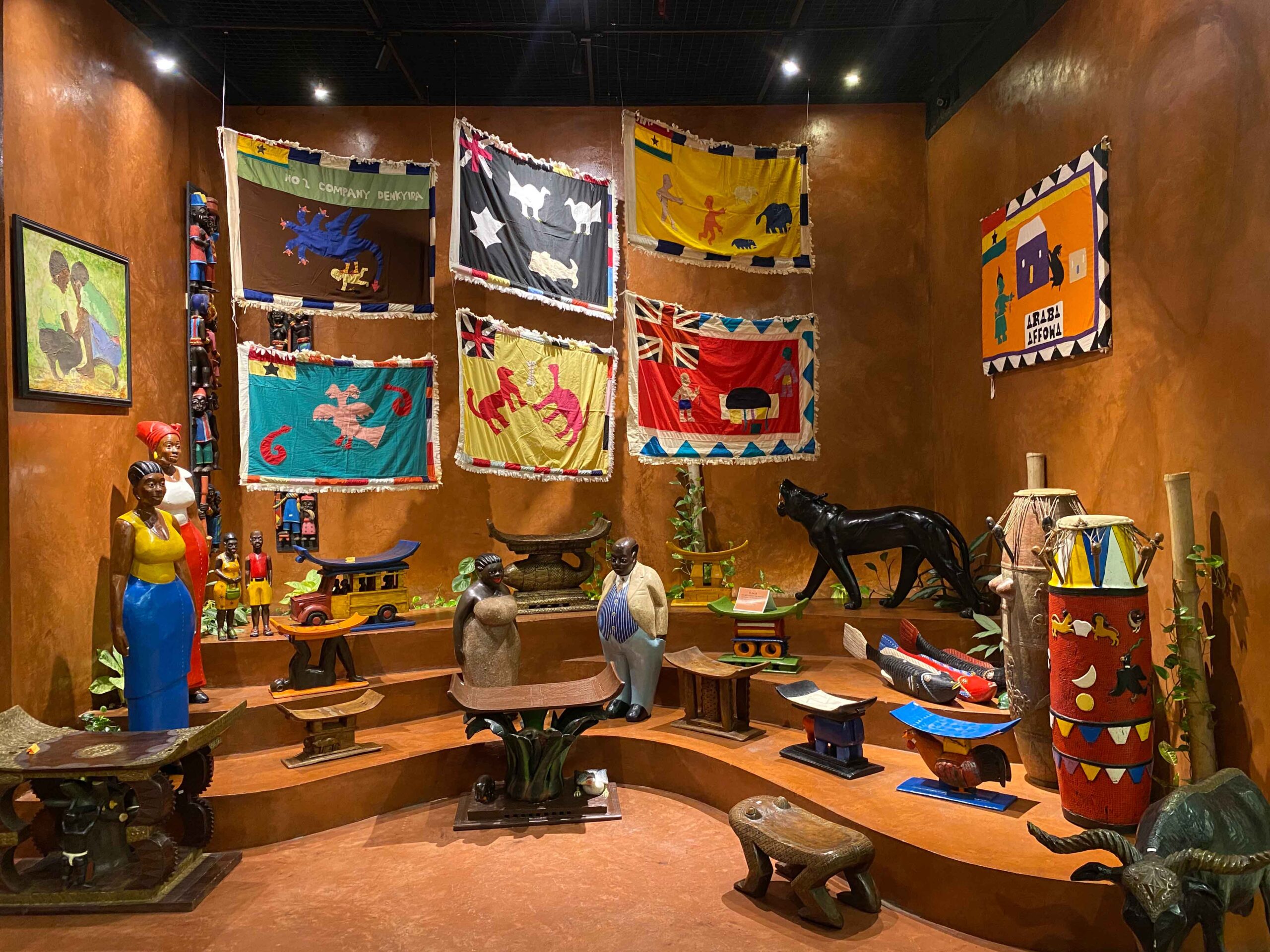 A Display Of Asafo Flags & Stools